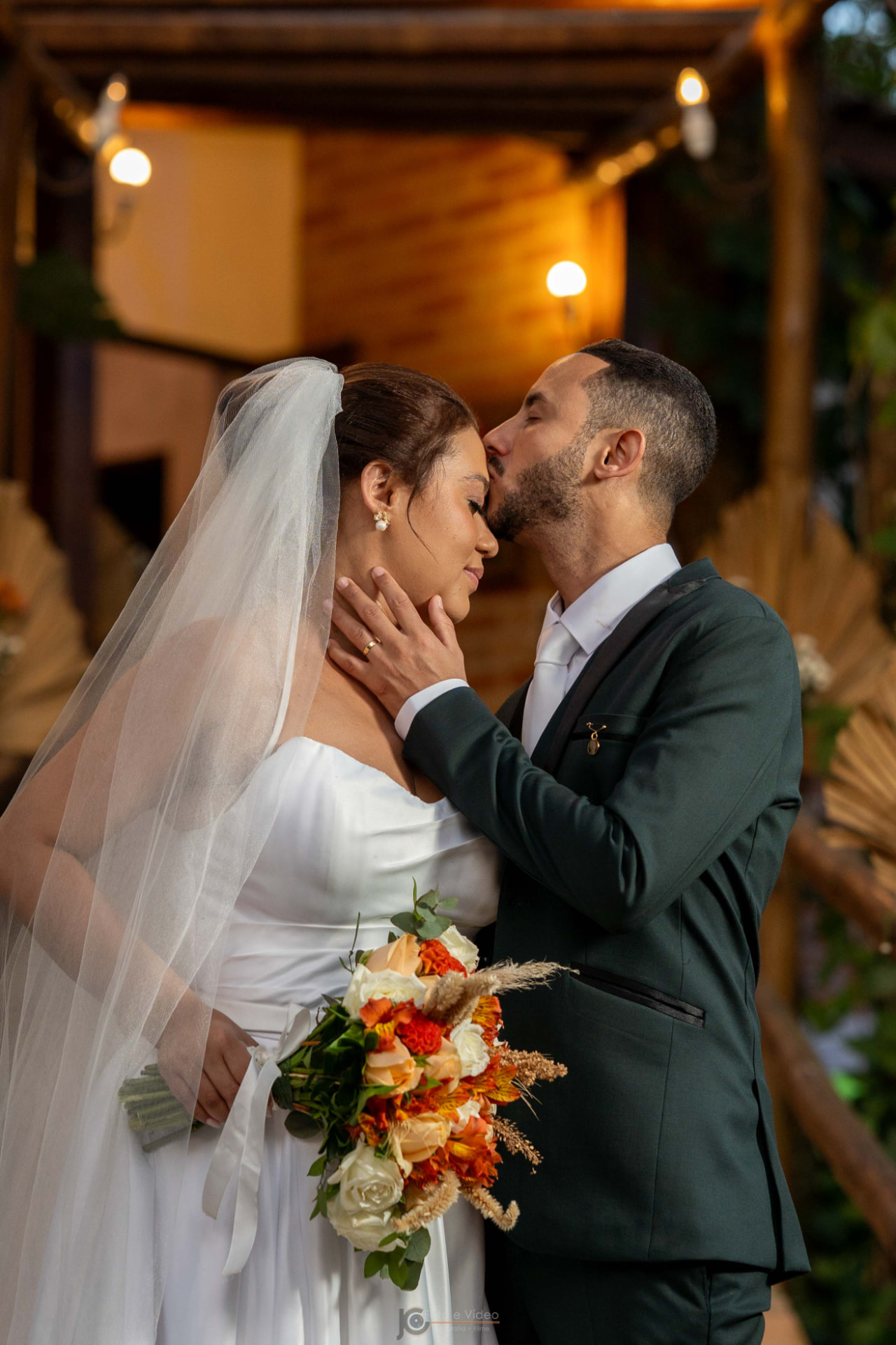 Noivo beijando a testa da noiva ao entardecer